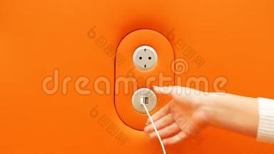 女孩将智能手机插入橙色墙上的<strong>USB充电</strong>端口